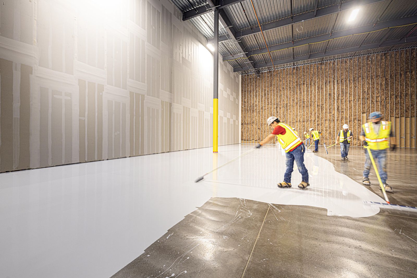 Workers installing a fresh white epoxy floor coating