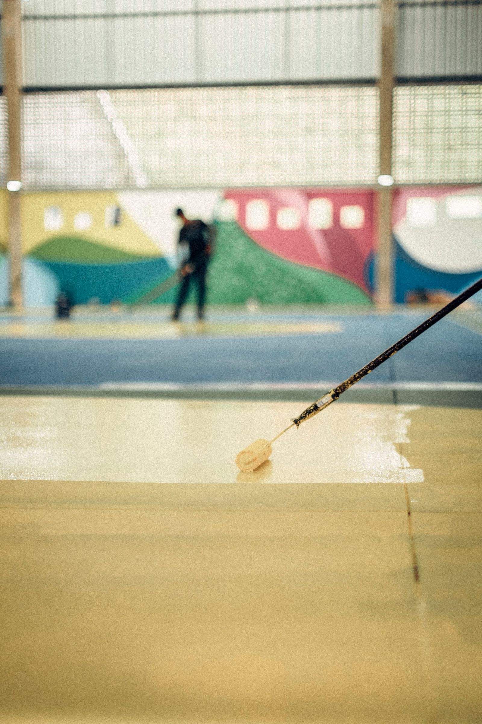 Crew applying glossy epoxy floor coating with a roller